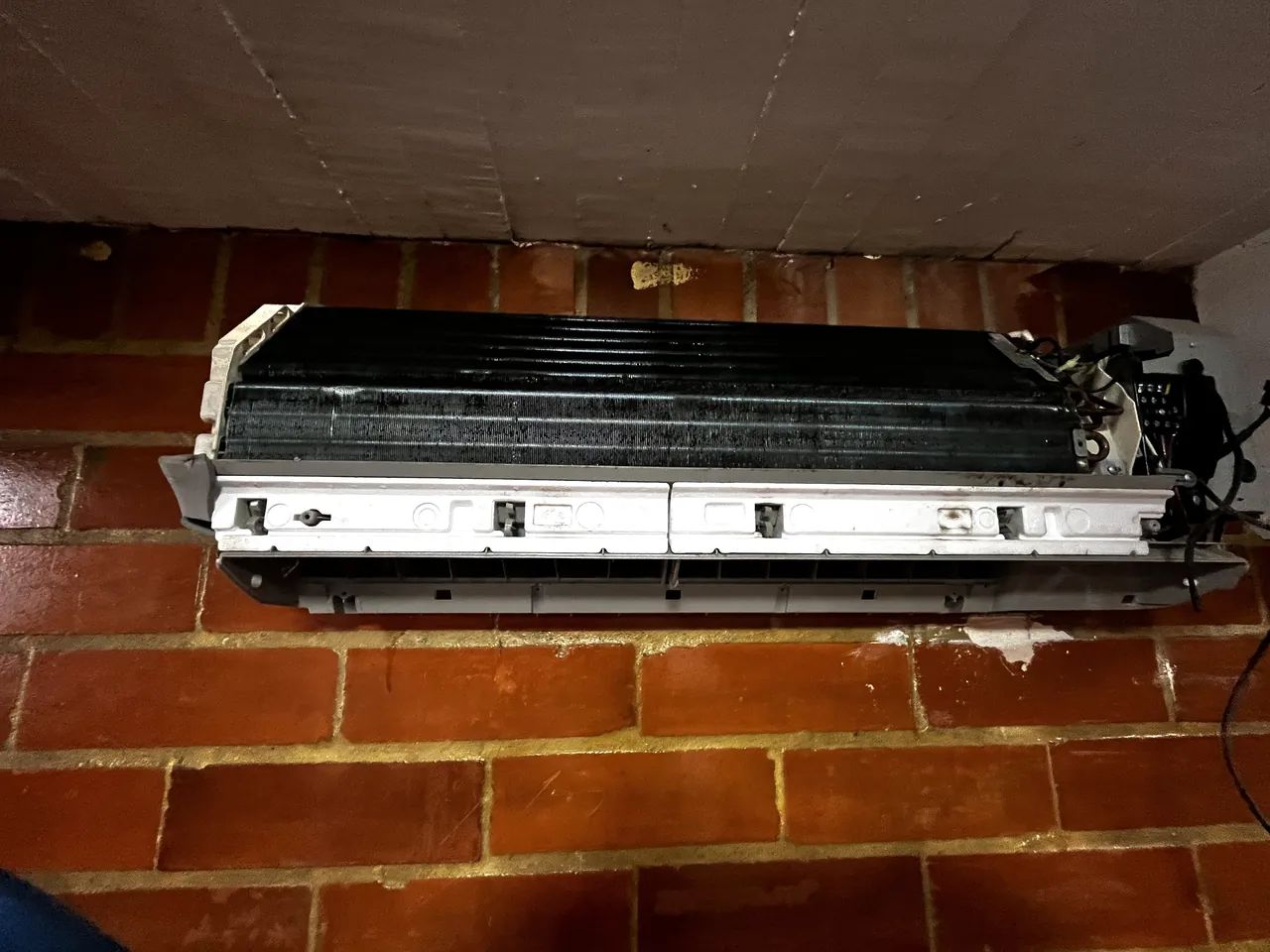 Evaporadora de aire acondicionado con la carcasa retirada, serpentín cubierto de polvo antes del mantenimiento