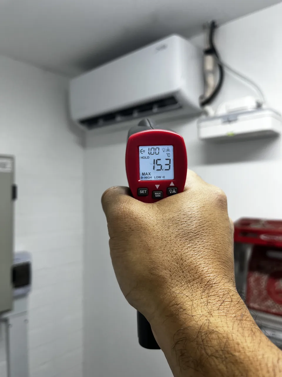 Termómetro infrarrojo midiendo la temperatura de suministro de un mini split instalado en pared
