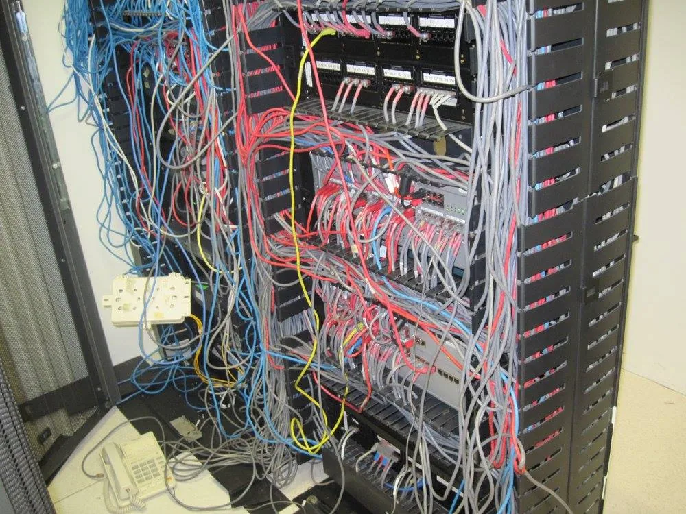 Otro cuarto técnico antes: cables de varios colores cruzando el rack sin canalizar