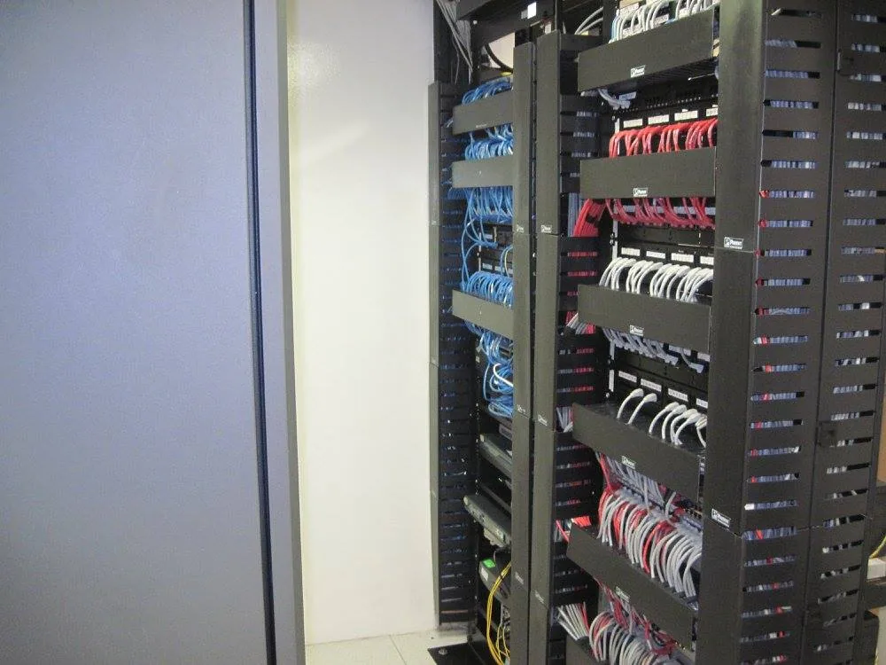 El mismo cuarto después: racks abiertos con organizadores horizontales y patch cords peinados por color