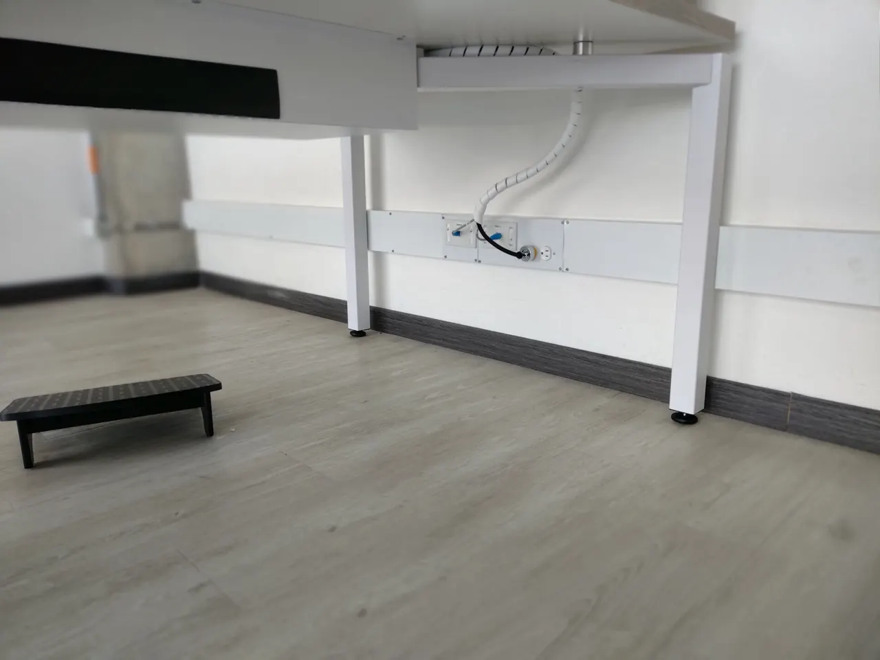 Puesto de trabajo terminado con canaleta perimetral, toma de datos, toma eléctrica y organizador de cable bajo el escritorio