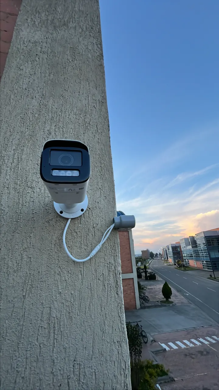 Cámara tipo bala instalada en la fachada de un edificio corporativo, cubriendo la vía de acceso