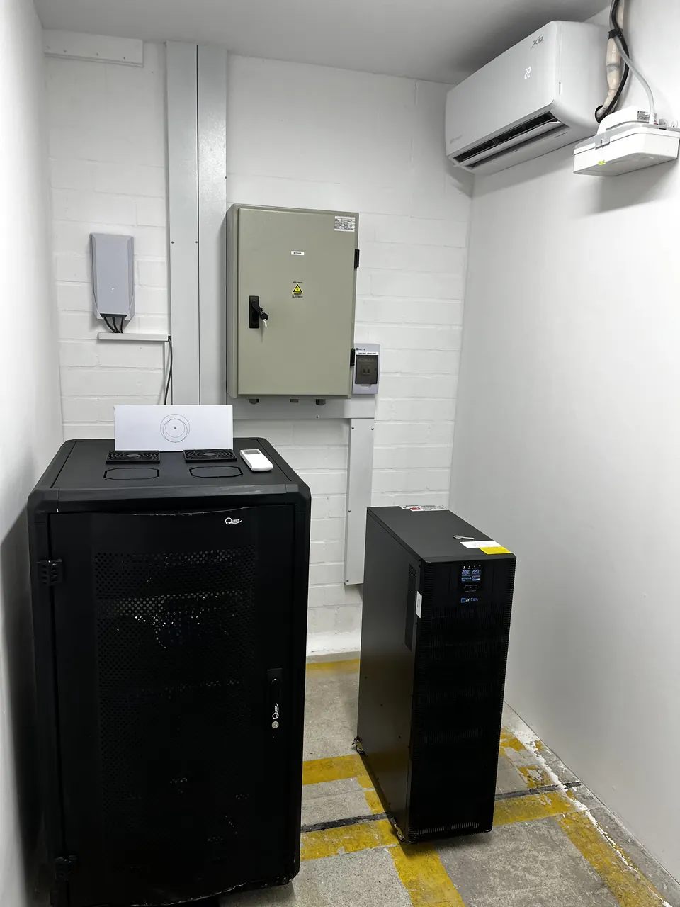 Cuarto técnico completo: gabinete cerrado, UPS, tablero eléctrico y aire acondicionado, con demarcación de piso