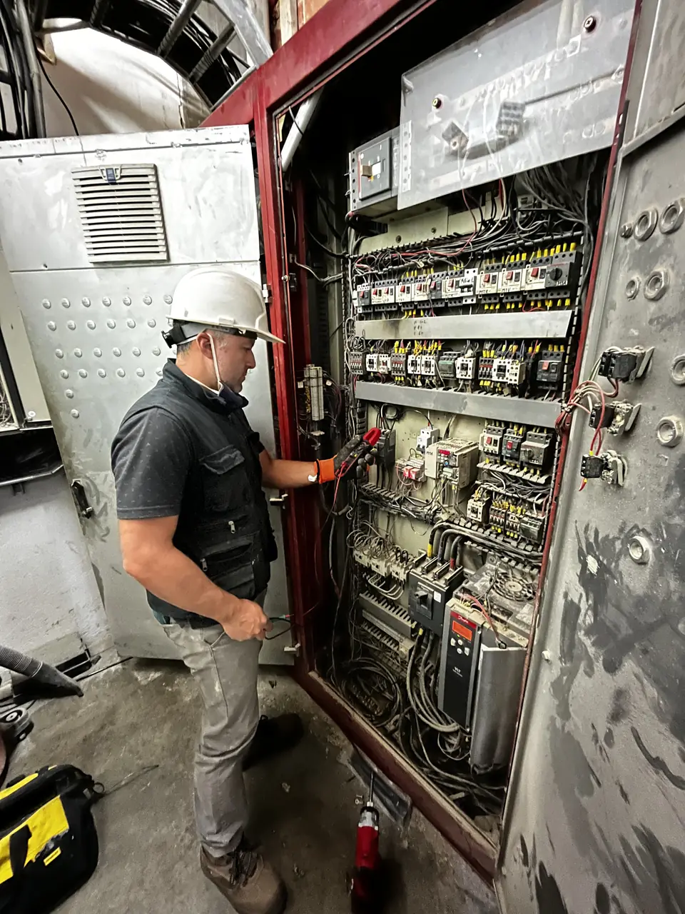 Técnico de RSI midiendo en un tablero de automatización dentro de una planta industrial