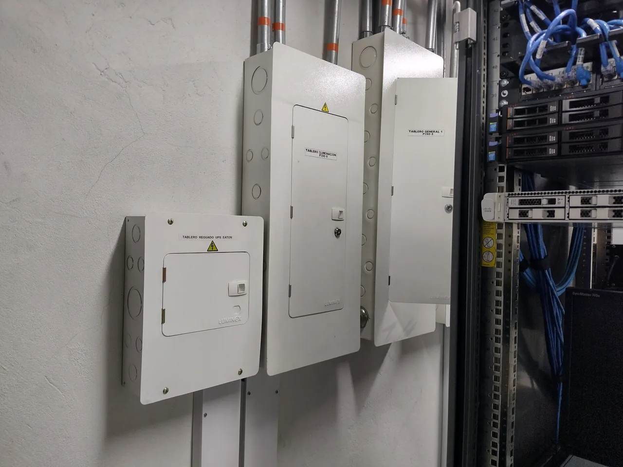 Tres tableros rotulados: regulado de UPS, iluminación y general, junto al rack de comunicaciones
