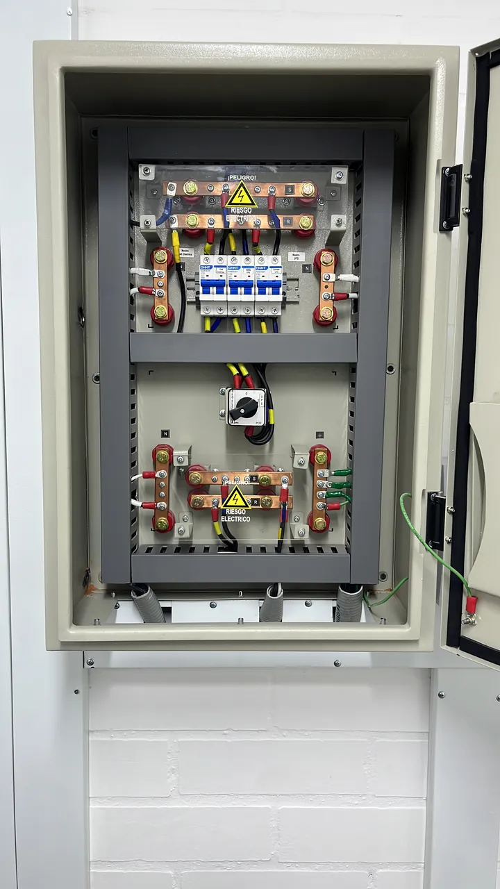 Tablero eléctrico principal en gabinete, con barrajes y señalización de riesgo eléctrico
