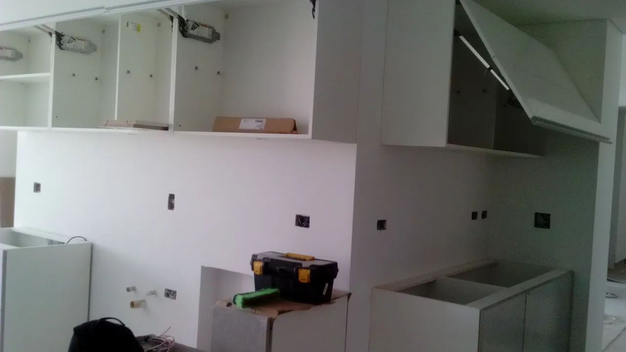 Muebles altos y bajos de carpintería a medida en pleno montaje, con las cajas de los puntos eléctricos ya abiertas en el muro