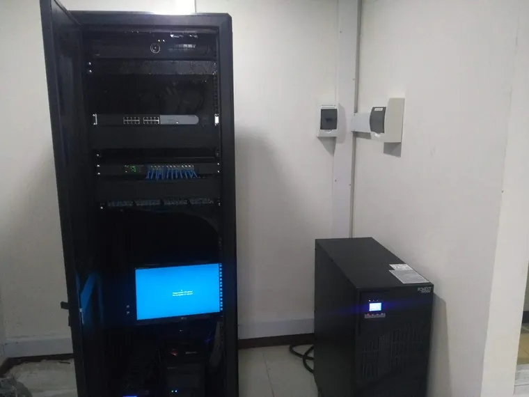Rack de comunicaciones abierto en Pereira, con switch, patch panels y monitor, y una UPS Powest Titan al lado