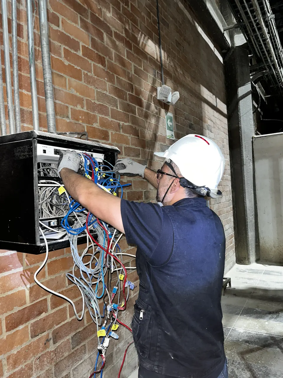 Técnico de RSI organizando el cableado de un rack de comunicaciones durante una intervención