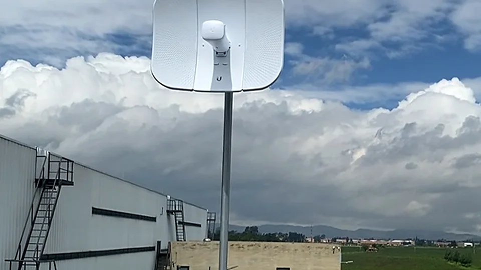 Antena de radioenlace montada en un mástil sobre la cubierta de una bodega, apuntando hacia el horizonte despejado